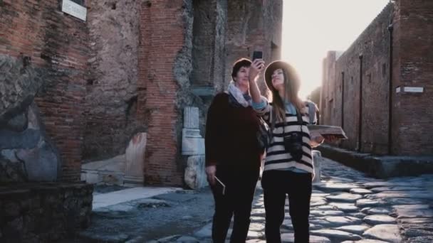 Šťastný matka Kavkazský a dcera se selfie fotografie při průzkumu staré antické ulice Pompeii, Itálie společně. — Stock video