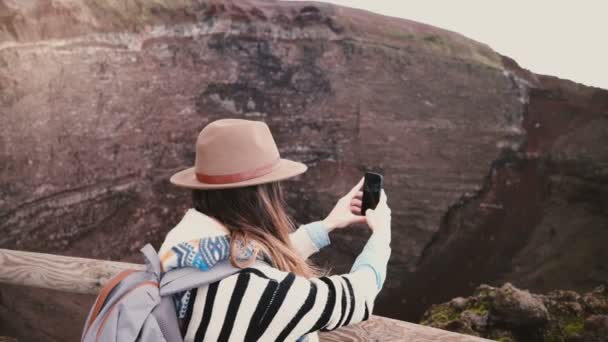 Νέοι ευτυχισμένος ελεύθερος επαγγελματίας κορίτσι με σακίδιο λαμβάνοντας smartphone φωτογραφίες του κρατήρα του ηφαιστείου Βεζούβιου σε διακοπές στην Ιταλία. — Αρχείο Βίντεο