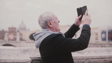 Smartphone yavaş hareket kullanarak Roma, İtalya antik şehir binaların fotoğraf çekme mutlu heyecanlı kıdemli erkek turist.
