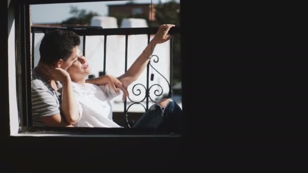 Mooie jonge multi-etnisch paar zitten samen aan mooie romantische zonnige appartement balkon genieten van het uitzicht. — Stockvideo