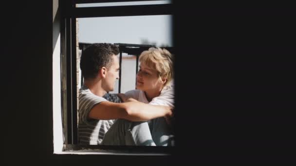 Feliz hombre y mujer multiétnicos sentados juntos en un hermoso balcón soleado, mirándose, hablando de la vida . — Vídeos de Stock