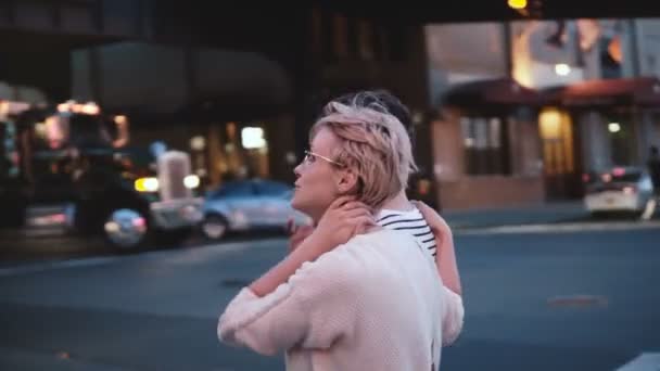 Happy European girl shows something to her Hispanic boyfriend, he nods to agree. Couple on evening street in New York. — Stock Video