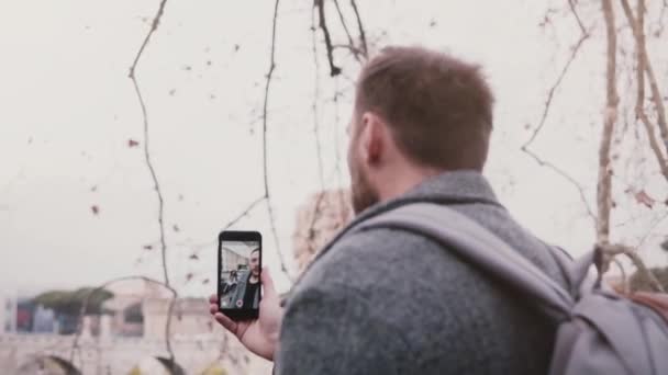 Mladý úspěšný kavkazských video blogger natáčení sám pomocí smartphone při chůzi na ulici v zimě Řím. — Stock video