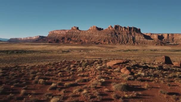Беспилотник летит низко над сухой песчаник пустыни и грузовик на небольшой дороге, удивительные американские солнечные равнинные горы горизонта . — стоковое видео