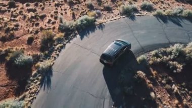 Üstten görünüm dron sırayla küçük dar asfalt çöl çevre yolu üzerinde bir güneşli yaz gününde gümüş steyşın araba takip eder..