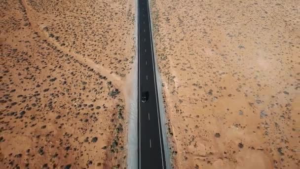 美しい自然の景観パターンを持つアメリカの砂漠の真ん中で高速道路に沿って運転している車の空撮. — ストック動画