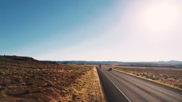 Drone vliegen laag boven de typische Amerikaanse woestijn snelweg platteland weg met auto's voorbij en verbazend heldere hemel. — Stockvideo