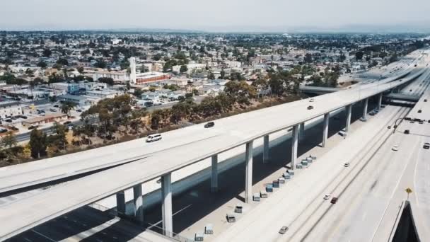 Drone tournant à gauche, révélant étonnante banlieue américaine skyline et grand échangeur de jonction d'autoroute occupé avec la circulation — Video