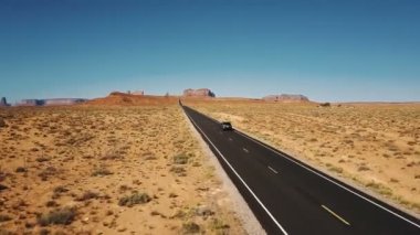 Drone gümüş renkli araba şaşırtıcı Amerikan çöl manzara, Anıt Vadisi, ABD boş Otoban yol boyunca sürüş izler.