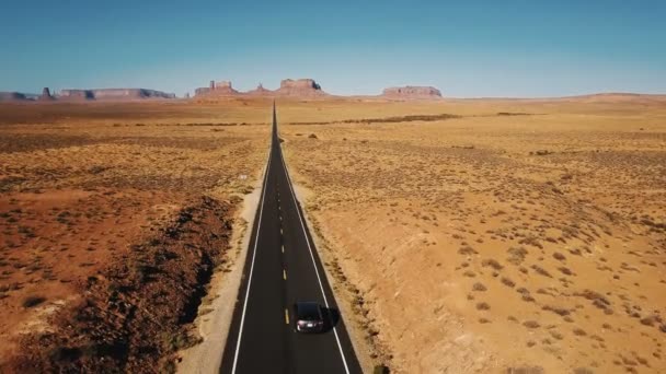 Increíble toma aérea de coche plateado conduciendo a lo largo de la increíble carretera del desierto de piedra arenisca estadounidense en Monuments Valley, EE.UU. . — Vídeo de stock