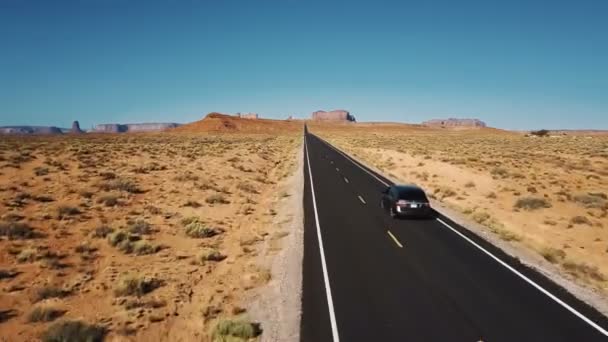Όμορφη κεραία βολή της ασημί αυτοκίνητο οδήγηση κατά μήκος το εκπληκτικό αμερικανική έρημο δρόμο προς βουνά στο Monument Valley. — Αρχείο Βίντεο