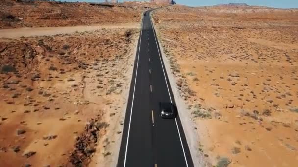 Drone volgwagen zilver op lege woestijn snelweg weg in Arizona, camera kantelt omhoog te onthullen vlakke landschap en skyline — Stockvideo