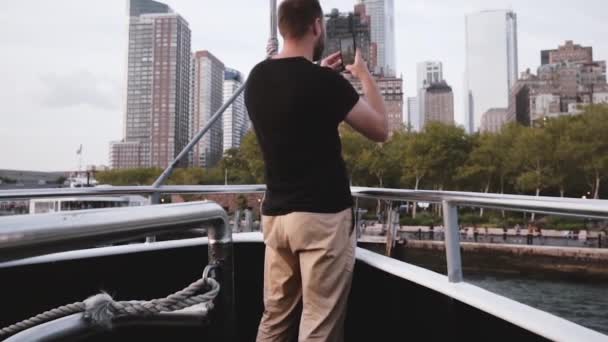 Emocionado turista masculino caucásico haciendo un vídeo de teléfono inteligente de la ciudad de Nueva York vista del horizonte en un viaje en barco a cámara lenta . — Vídeos de Stock