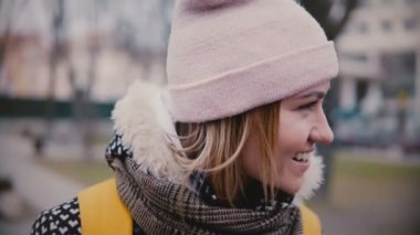 Yakın çekim yan görünümü yaşam tarzı kış şapkalı gülümseyen ve mutlu, o zaman ciddi genç güzel Avrupa Kız portresi.
