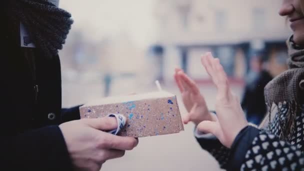 Nahaufnahme eines glücklichen gutaussehenden jungen kaukasischen Mannes, der seiner Freundin an einem verschneiten Weihnachtstag eine Geschenkbox schenkt — Stockvideo