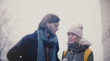 Mutlu rahat genç romantik çift rahat sıcak giysiler içinde beraber yürüyelim, sarılmak ve öpmek karlı bir kış Noel günü.