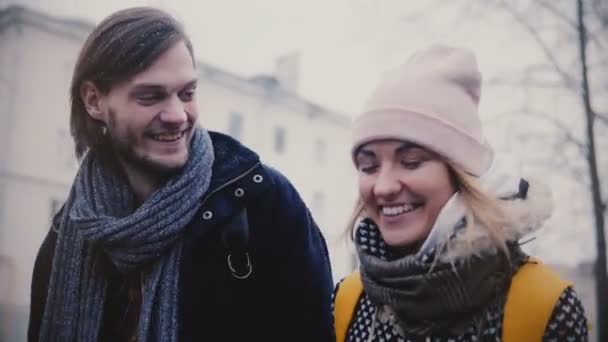 Крупный план двух счастливых расслабленных кавказских друзей, идущих, говорящих и улыбающихся на улице в холодный снежный зимний день — стоковое видео