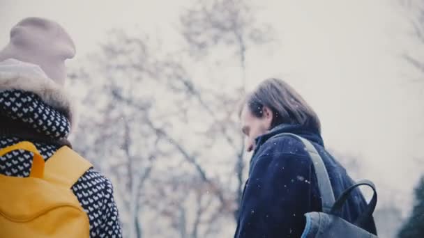 Tillbaka närbild av två glad avslappnad kaukasiska vänner promenader tillsammans och leende utanför på kall snöig vinterdag. — Stockvideo