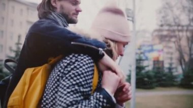 Ağır çekim mutlu rahat genç romantik çift birlikte sarılma, el ele tutuşarak ve karlı kış gününde gülümseyen yürüyüş.