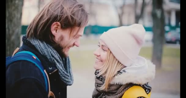 Feliz joven y sonriente pareja romántica europea de pie juntos mirándose en una cita en un frío día de invierno . — Vídeos de Stock
