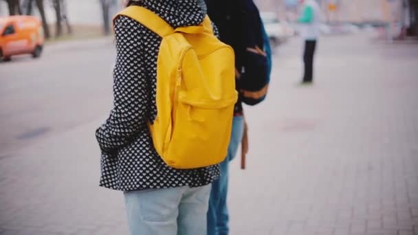 Vista posteriore di uomo e donna locale con zaino giallo brillante stare vicino insieme in attesa di una fredda giornata invernale nevosa . — Video Stock