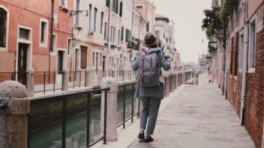 Mutlu genç şık Avrupa kadın turist ile ünlü eski canal sokağına Venedik İtalya boyunca yürüyüş zevk fotoğraf makinesi.
