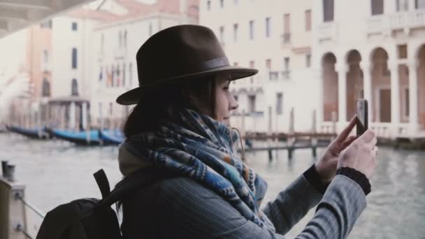 Glada vackra Europeiska kvinnlig turist tar smartphone bilder på en gondol utflykt tur längs fantastiska Venedig kanaler — Stockvideo