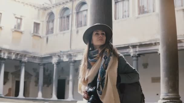 Красиві жіночі Туристична з камерою, ходьба і дивлячись на терасі старовинною будівлею з антикварних стовпів у Венеції. — стокове відео