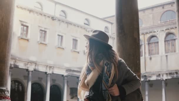 Glückliche professionelle Bloggerin mit Kamera, die ein Foto macht, während sie an einem antiken Gebäude mit Säulen in Venedig Italien spaziert. — Stockvideo