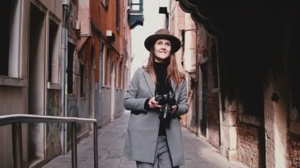 Aantrekkelijke gelukkig professionele journalist vrouw lopen met camera langs mooie straat in Venetië, nemen foto. — Stockvideo