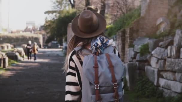 Cámara sigue a joven viajera en sombrero con mochila explorando ruinas del Foro en Roma, Italia en viaje de vacaciones . — Vídeos de Stock