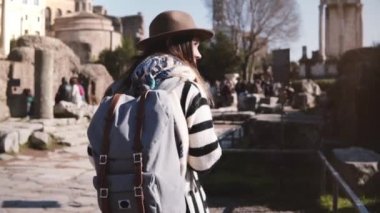 Genç rahat rahat kadın turist sırt çantasında şık giysiler de Roma Forumu manzaranın tadını yürüyüş ile.