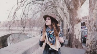 Roma ağır çekimde çınar ağaçlarının altında sonbahar Tiber Nehri banka boyunca yürüyüş sırt çantası ile genç düşünceli turist kız.