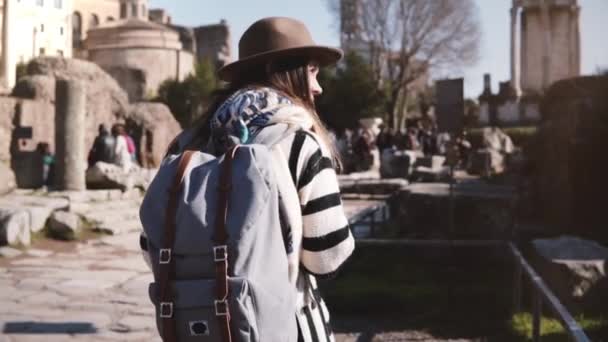Junge lässig entspannte Touristin mit Rucksack in stylischer Kleidung spaziert am Forum Romanum und genießt die Landschaft. — Stockvideo