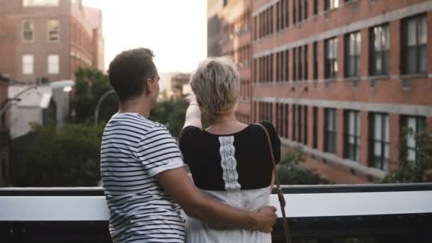 Krásný mladý romantický pár stojící a na most mluvit, objímání, těší úžasné scenérie New York City.