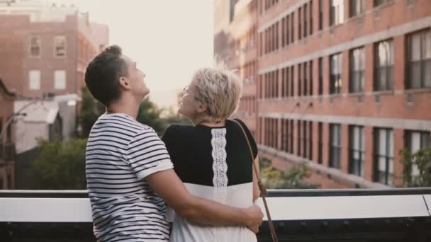 Gelukkige romantisch paar permanent nauwe en knuffelen, praten en genieten van prachtig uitzicht van de Brooklyn Bridge in New York City. — Stockvideo