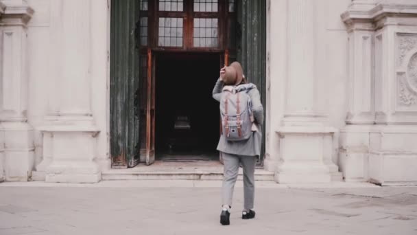 Cámara sigue joven turista femenina de moda caminando en las puertas de la catedral de San Marco en Venecia, Italia cámara lenta . — Vídeo de stock