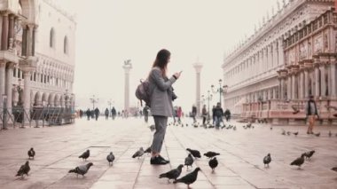 Geniş mutlu kadın turist smartphone üzerinde şaşırtıcı San Marco kare çekim shot tam kuşların Venedik, İtalya.