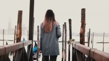 Arkadan Görünüş fotoğraf çekmek ve Venedik İtalya'gülümseyen bir gondol iskelede yürüyüş mutlu güzel fotoğrafçı kadın.