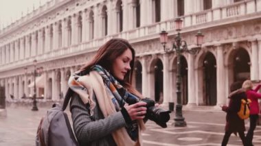 Güzel kadın seyahat blogger ile Venedik İtalya binalarda St Mark fotoğrafını çekmek, ağır çekim gülümseyen fotoğraf makinesi.