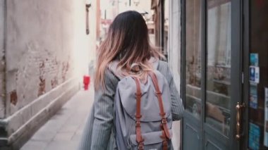 Fotoğraf makinesi şık kadın turist sırt çantası ve uzun saç eski yaz Venedik ağır çekimde sokak boyunca yürüyüş ile takip eder..