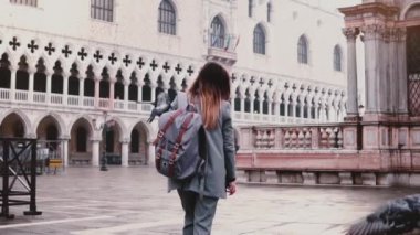 Venedik ağır çekimde kolundaki oturan güvercin ile San Marco Meydanı yürüme mutlu güzel beyaz kadın turist.