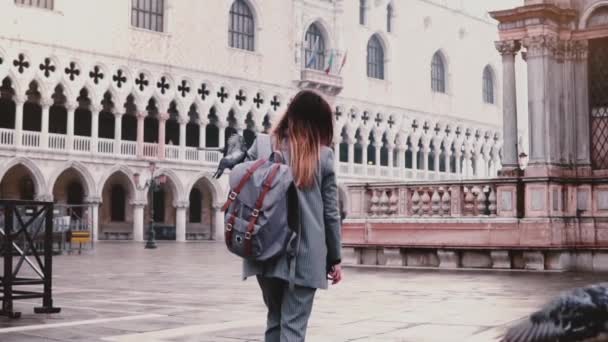 Happy beautiful Caucasian female tourist walking on San Marco square with pigeon sitting on arm in Venice slow motion. — Stock Video