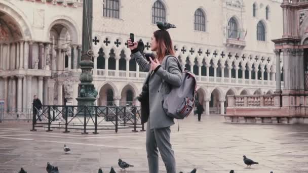 Boldog mosolygó női turisztikai galambok ül a karját, és a fejét úgy selfie a város főterén, Velence-lassú mozgás.