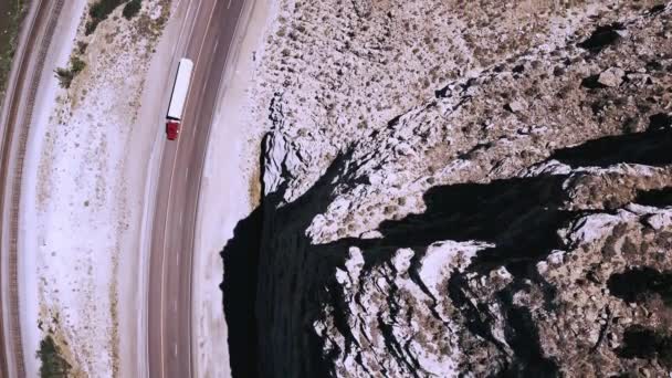 Bovenaanzicht drone draaien pal boven prachtige snelweg weg en spoor nummers gaan in de buurt van epische rotsachtige zandstenen bergen. — Stockvideo