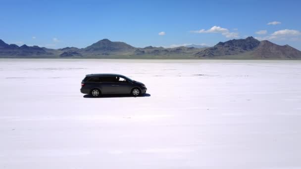 Drone sigue, se aleja del coche minivan de plata que conduce a lo largo de la increíble llanura desértica de lago salado en Bonneville, Utah . — Vídeo de stock