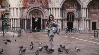 Güvercin ile smartphone Venedik, İtalya, ağır çekimde San Marco cathedral yakınındaki güzel kadın turistin kolundaki oturur.