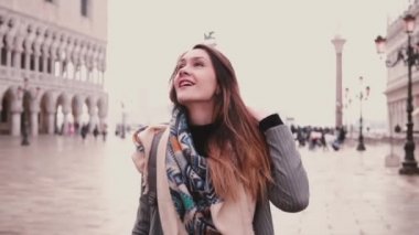 Güzel genç kadın turist heyecanlı geri dönüyor. Venedik, İtalya, ağır çekimde eski St Mark şehir meydanında gülümseyen.
