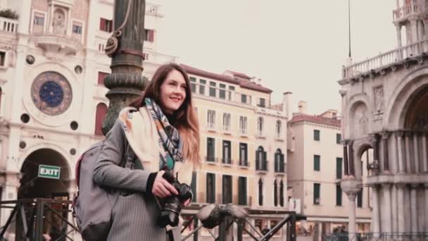 Feliz reportera emocionada con cámara camina en la plaza de otoño de San Marco y bandada de palomas en Venecia cámara lenta . — Vídeo de stock