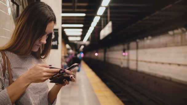 Grave bella donna stressata sulla piattaforma della metropolitana con smartphone e carta di credito che cerca di digitare i numeri . — Video Stock